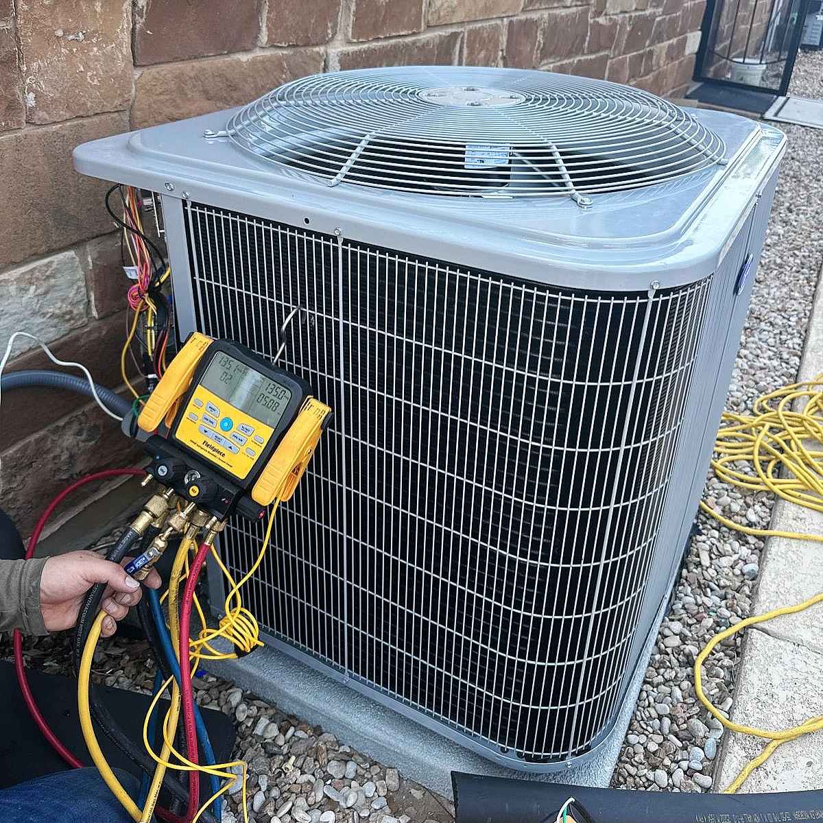 Global Air Service technician inspecting HVAC unit with gauges and safety gear